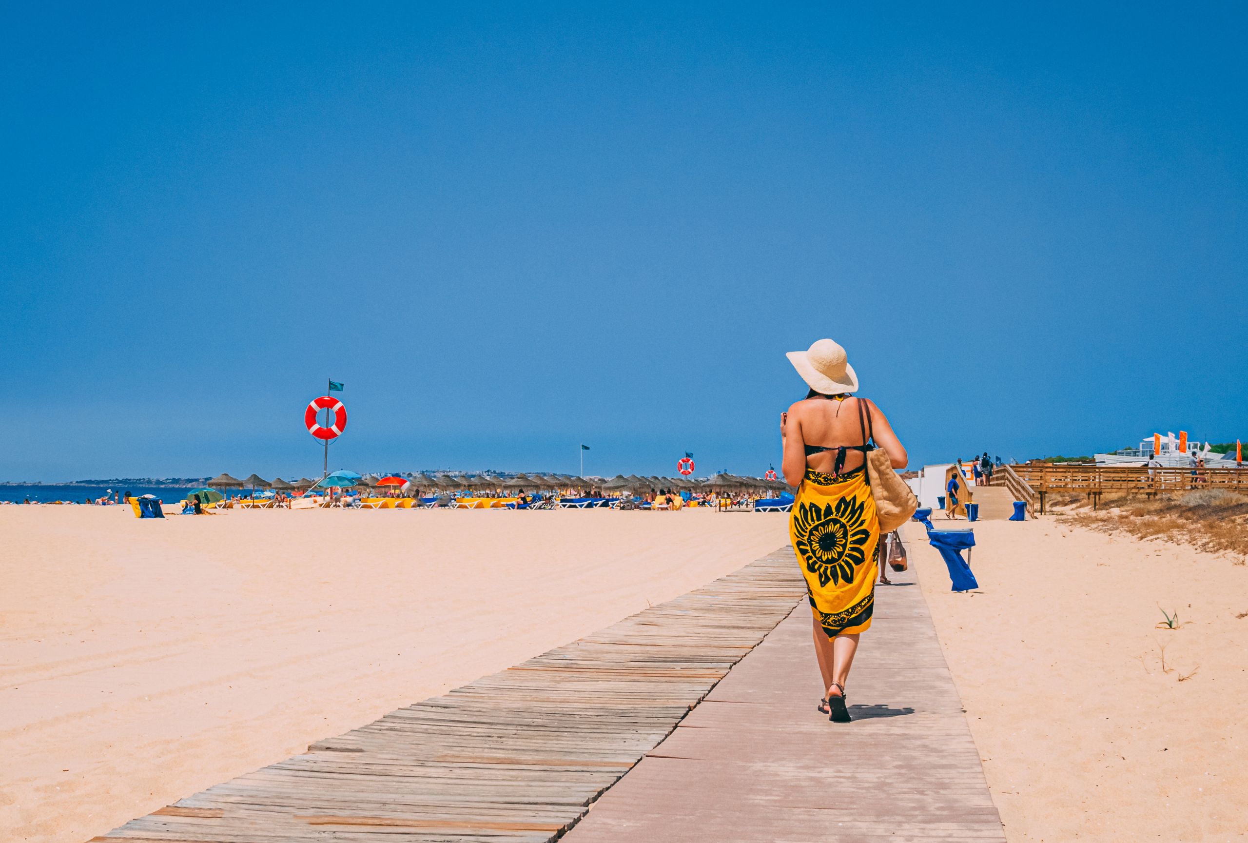 Mujer andando por la playa y mar al fondo como destino turístico del sur de España
